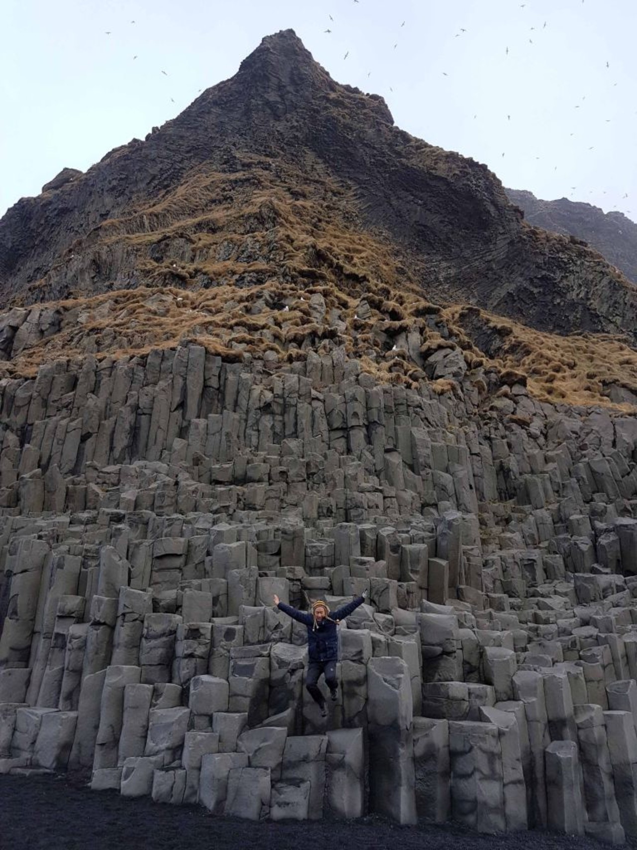 A woman jumping of a basalt columns at Reynisfjara in South Iceland