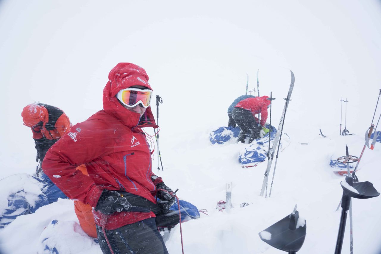A group of people packing their luggage in the snow and wind on a glacier on a poplar training course with Icelandic Mountain Guides