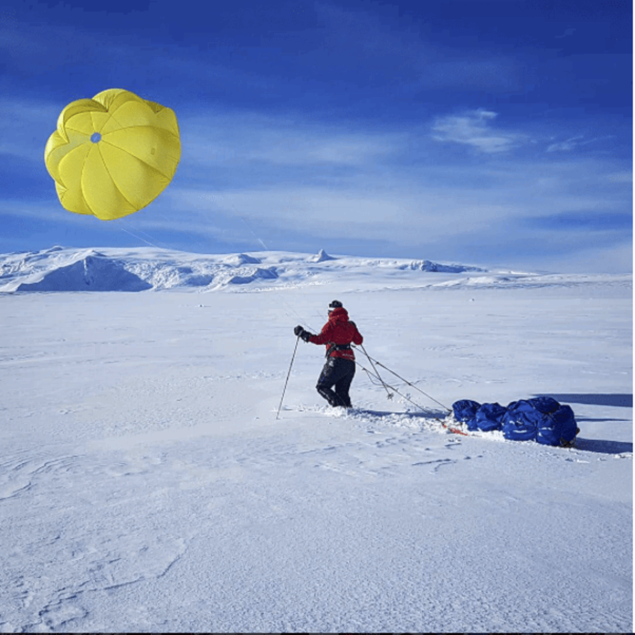 Mountaineer walking across glacier with a pulka and a kite on a course with Icelandic Mountain Guides.