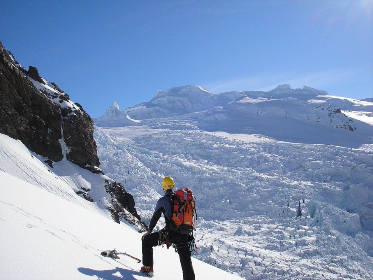 A hiker hiking the summit of Hrútfjallstindar and looking over to Hvannadalshnjúkur on a tour with Icelandic Mountain Guides