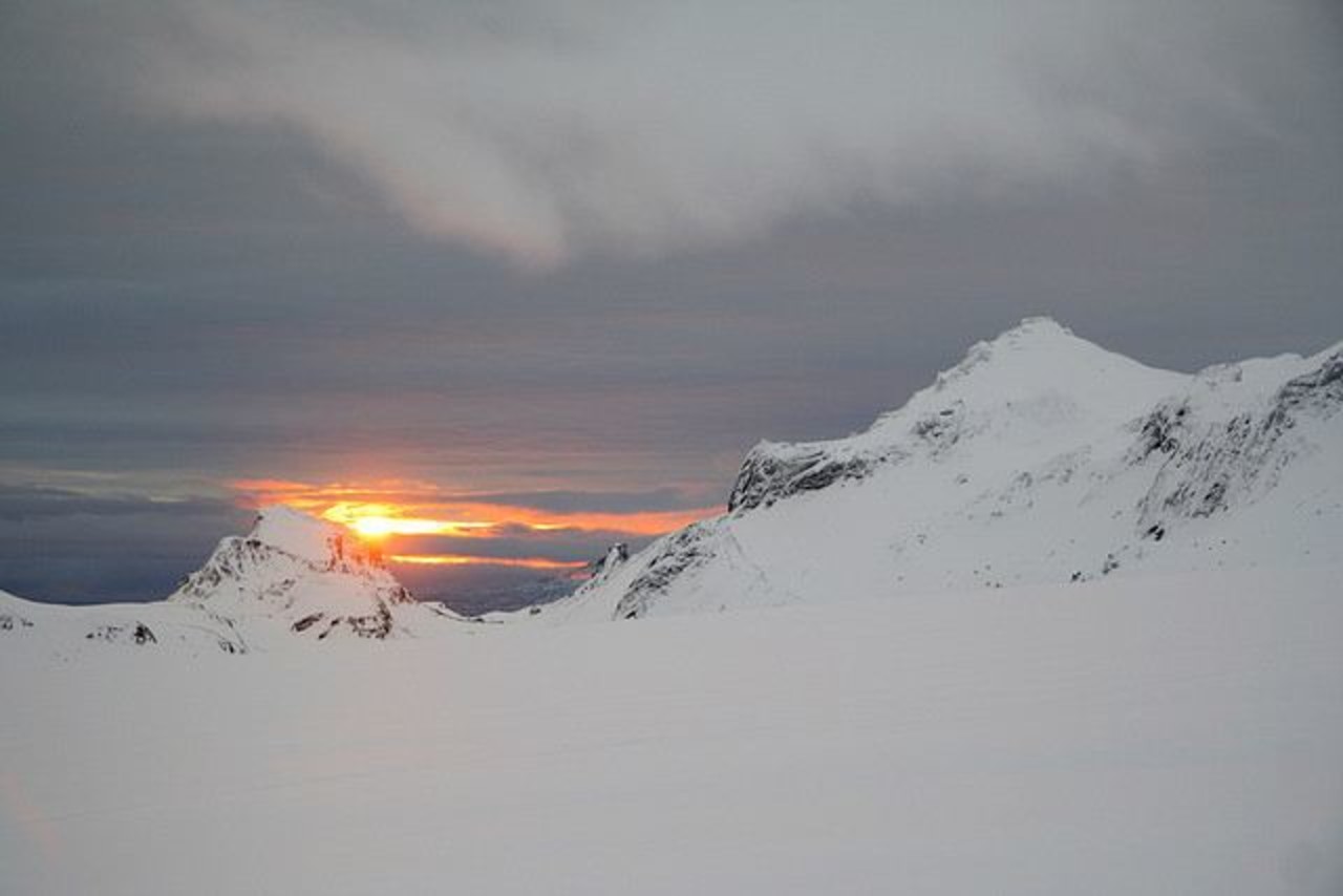 Sunset next to mountains covered with snow