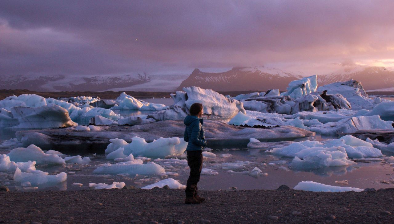 A woman standing on a rocky beach on a summers eve at Jökulsárlón on a tour with Icelandic Mountain Guidis