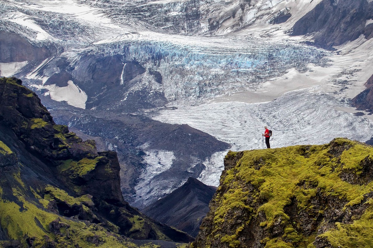 A hiker looking down at a glacier from a cliff in Laugavegur