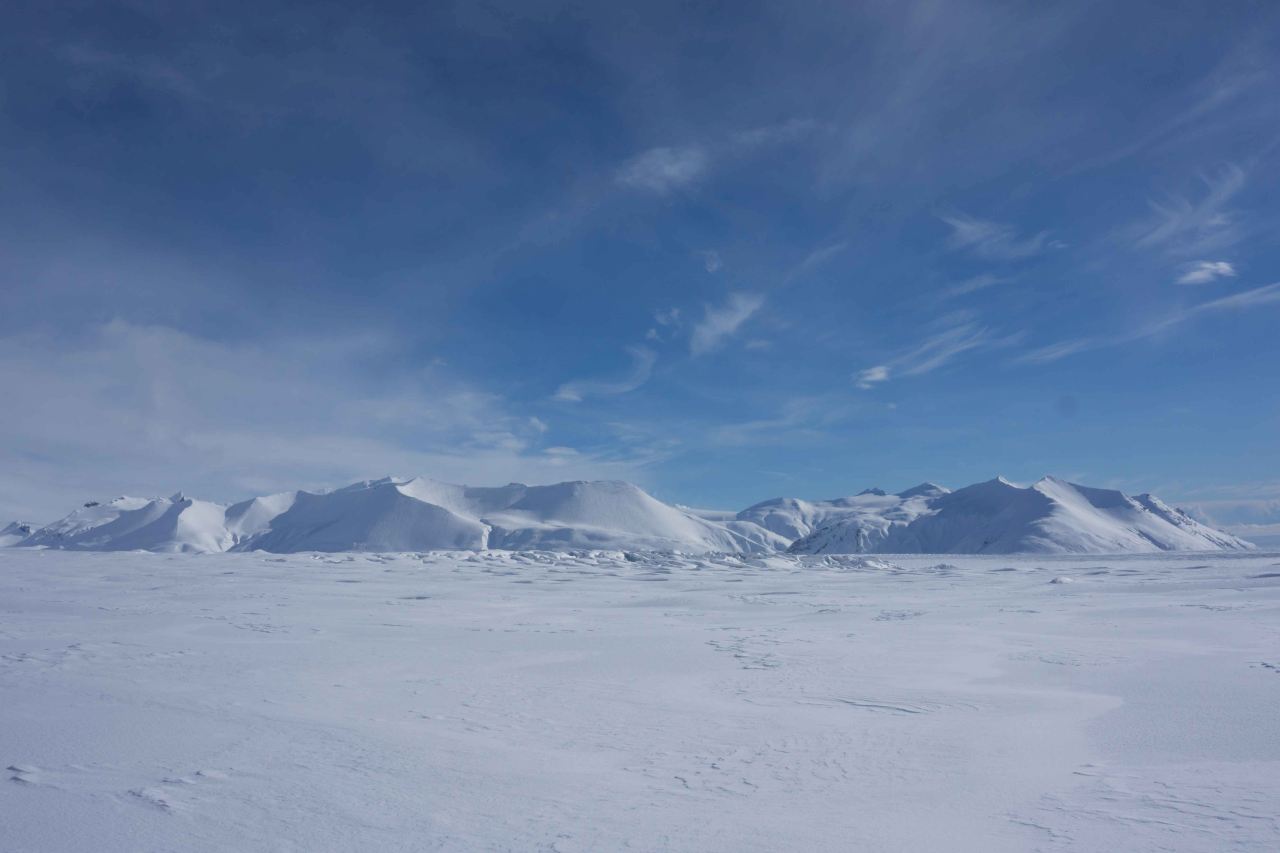 View over snowy mountains with a blue sky.