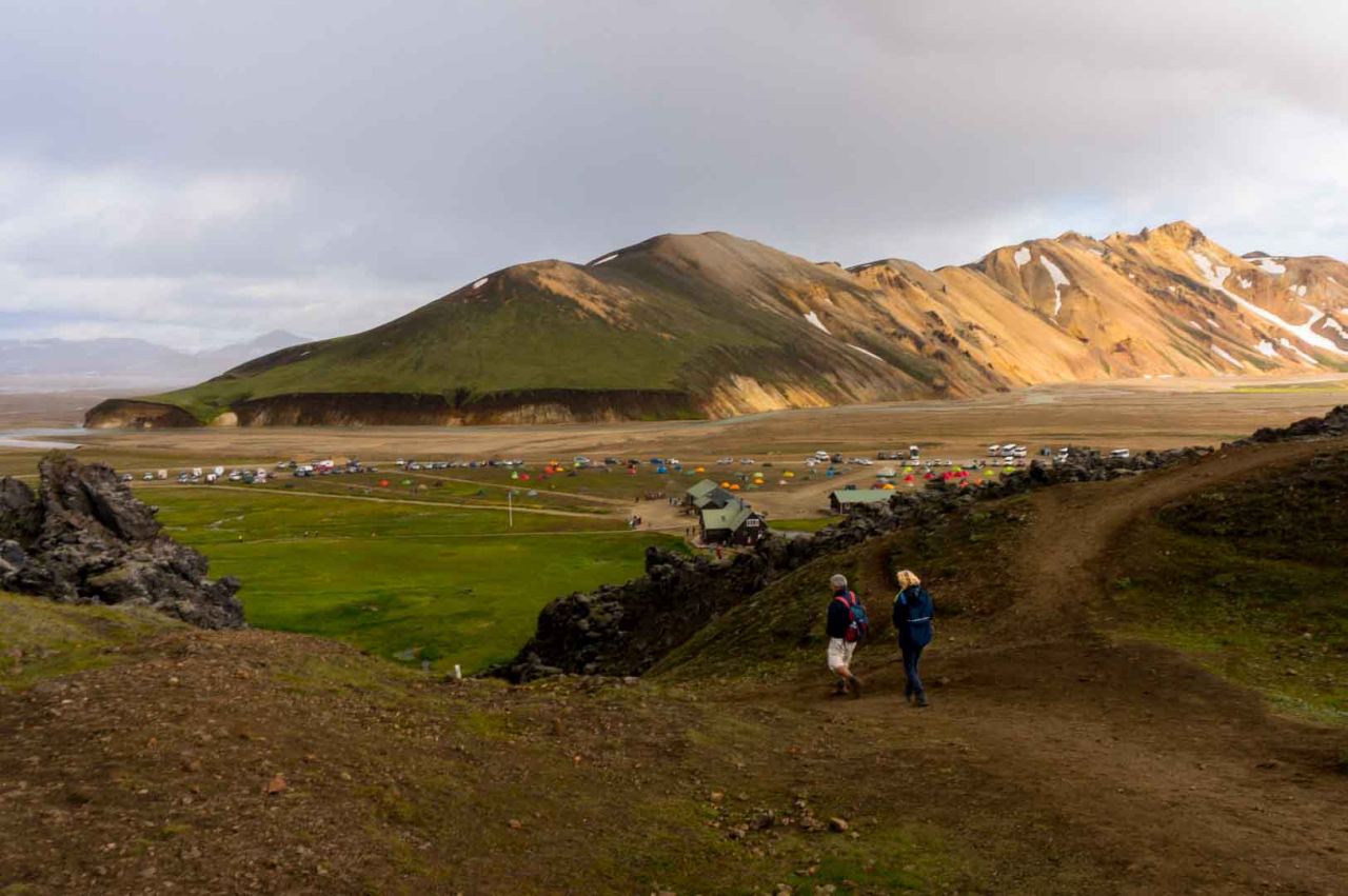Two people walking toward the camping grounds in Landmannalaugar in the Icelandic highlands